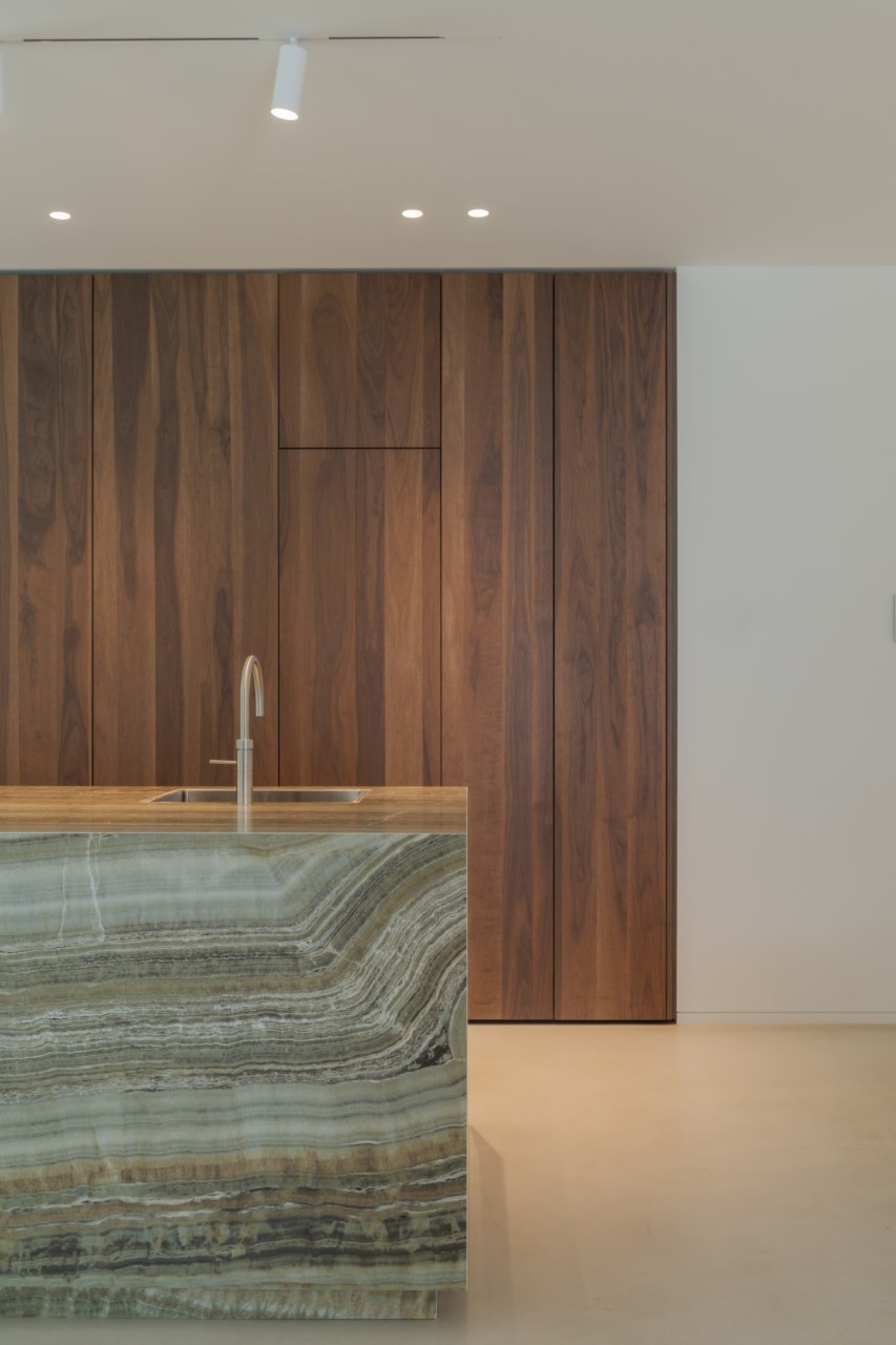 Minimalistische keuken, warme keuken, houten kastenwand, keramisch kookeiland, strakk interieurbouw