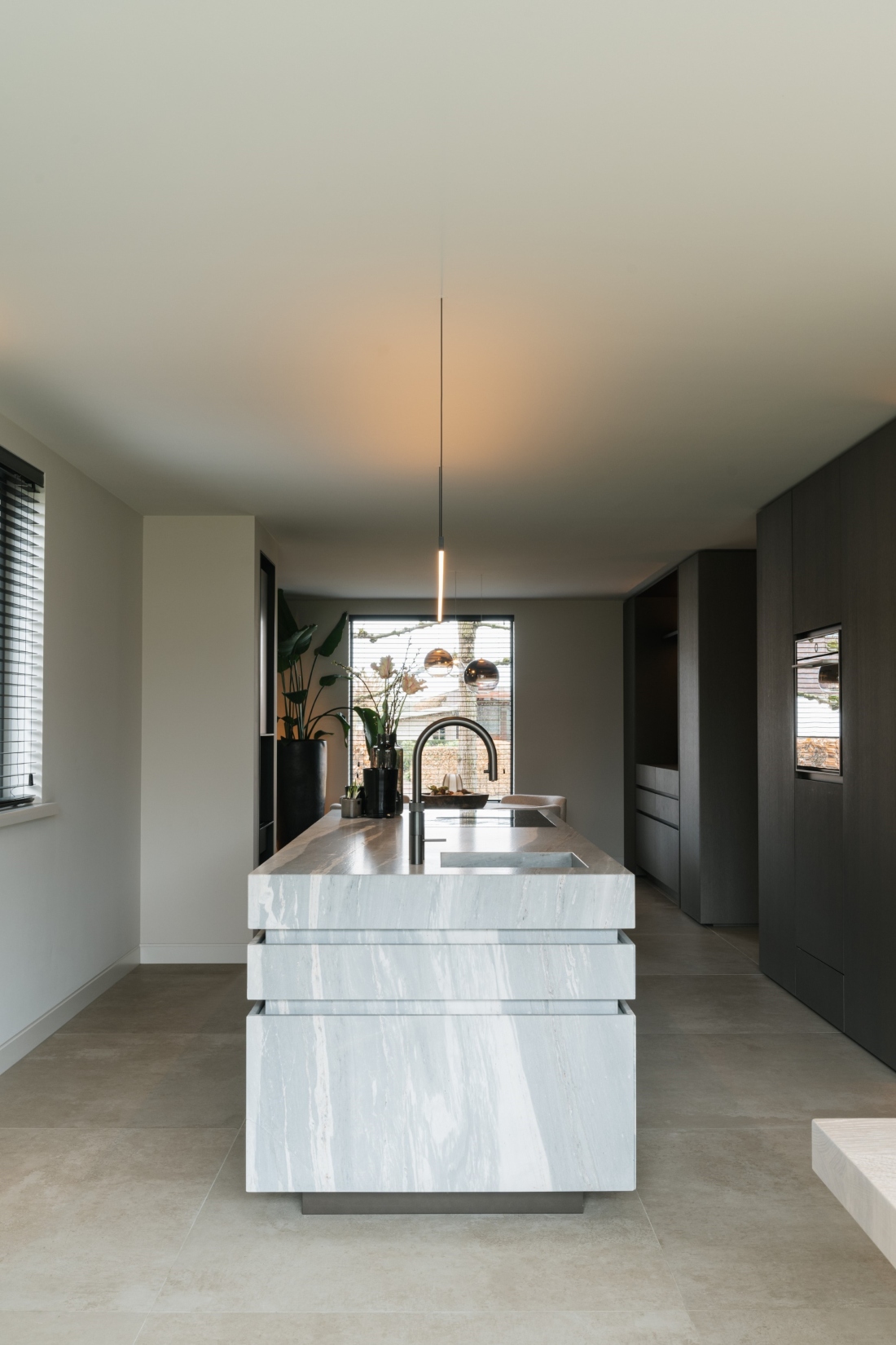 Kookeiland van kwartsiet in midden van de ruimte, lijnenspel, maatwerk keuken, strakk interieurbouw