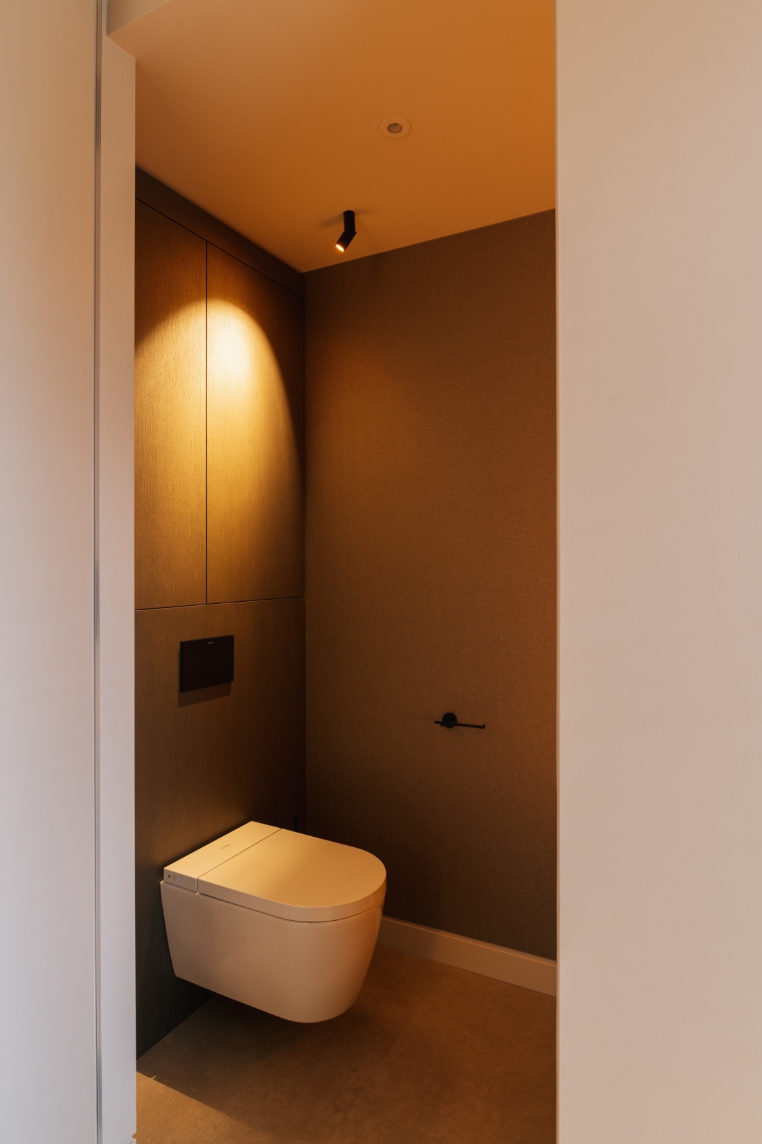 toilet met luxe arte-behang, zwarte accenten, strakk interieurbouw