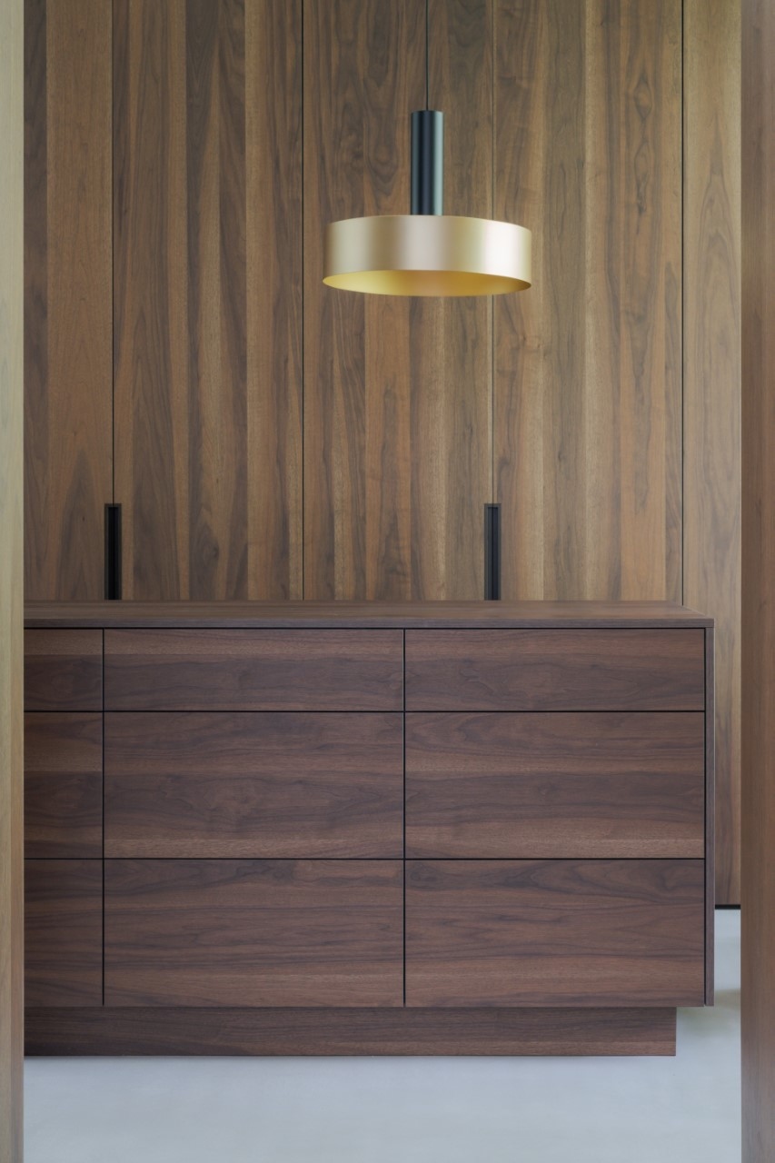 Luxe inloopkast welke is afgewerkt met verfijnd Shinokki-walnoothout, strakk interieurbouw, walk in closet.