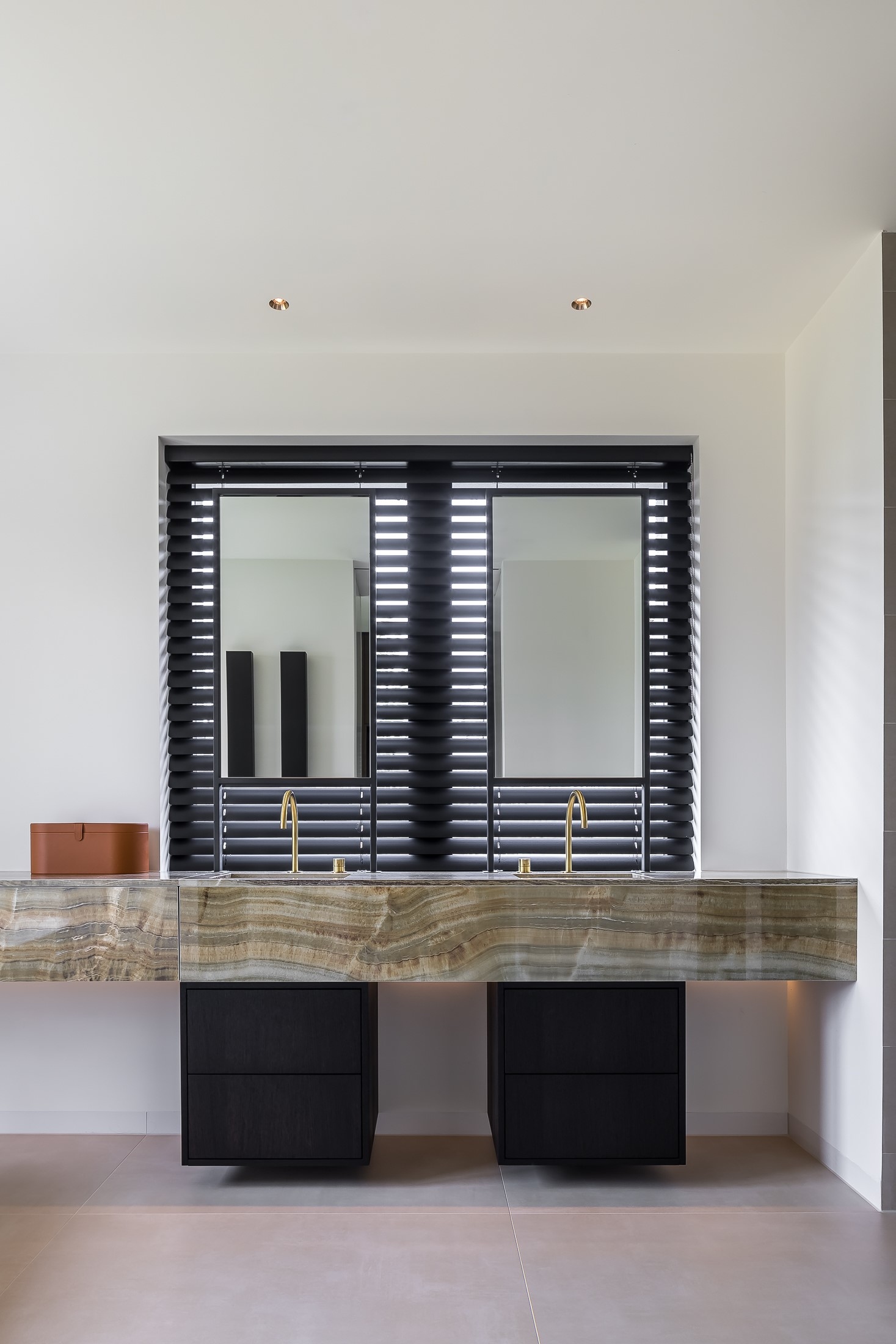 Moderne badkamer met dubbele wastafel, gouden kraan, dubbele spiegel, zwarte accenten, strakk interieurbouw